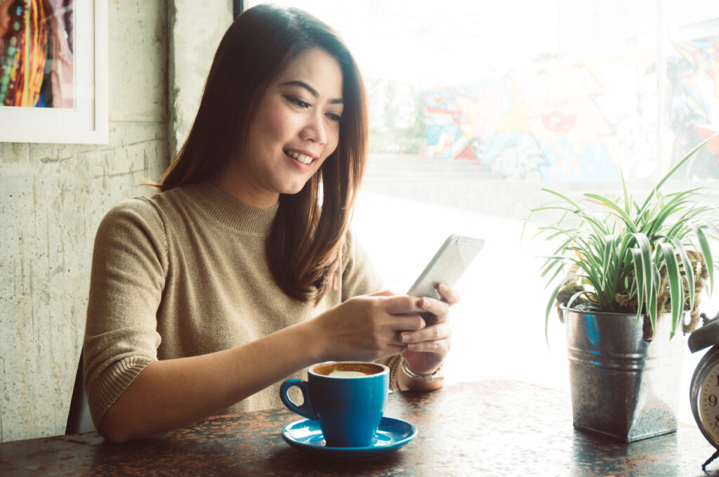 Asian woman shopping online with credit card payment in coffee shop feeling happy smile